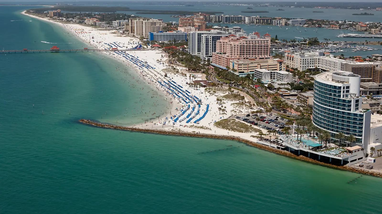 Aerial view of Clearwater Beach with white sand, turquoise water, hotels, and marina, near Tenth Rock headquarters